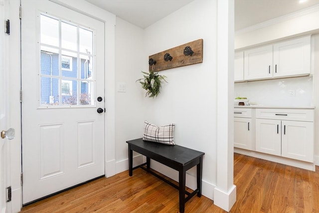 doorway featuring baseboards and light wood finished floors