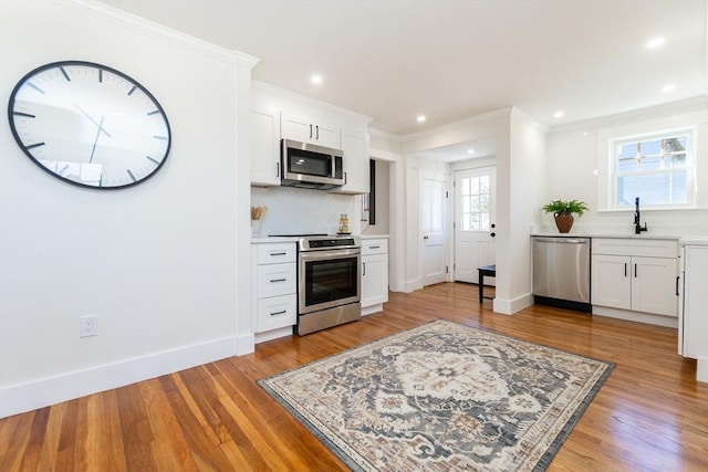 kitchen featuring a sink, tasteful backsplash, appliances with stainless steel finishes, and light wood finished floors