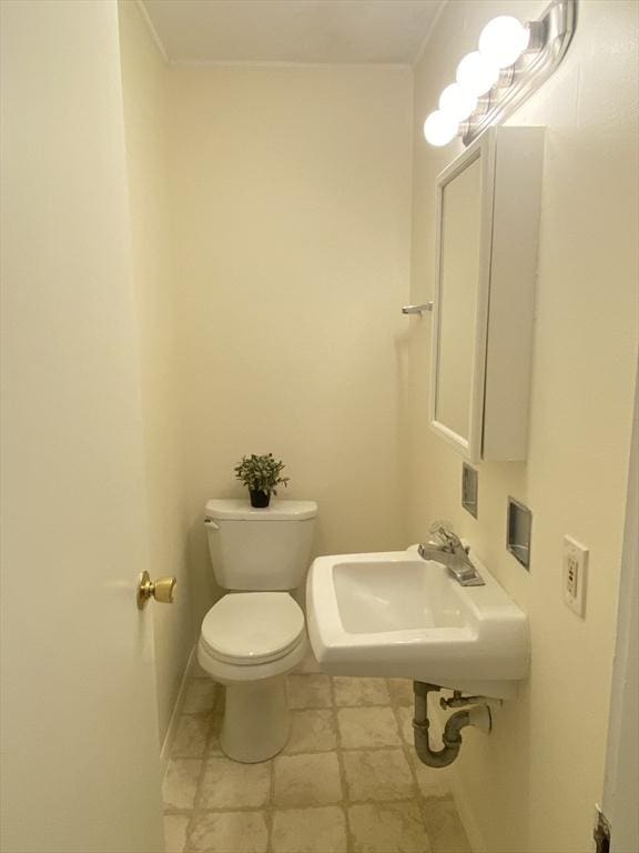 half bathroom with a sink, toilet, and baseboards