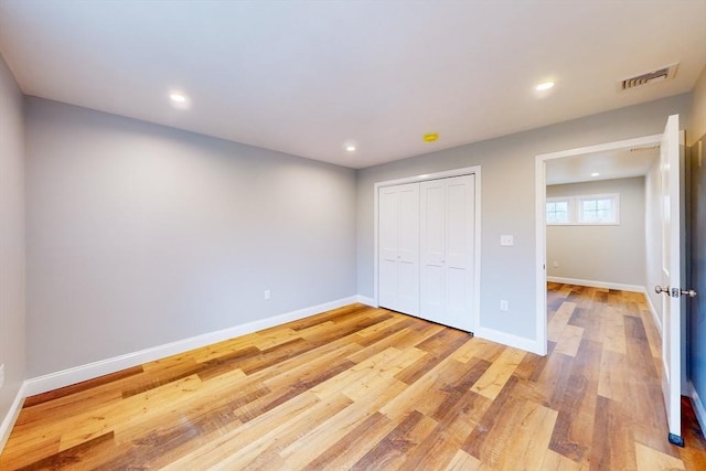 unfurnished bedroom with light hardwood / wood-style flooring and a closet