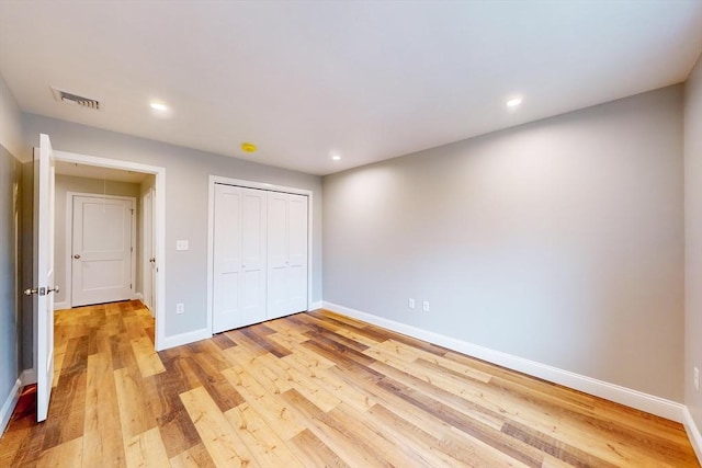 unfurnished bedroom with light wood-type flooring and a closet