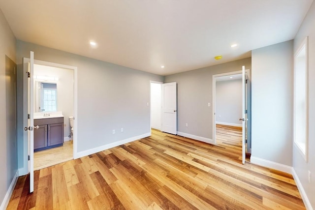 unfurnished bedroom featuring ensuite bathroom, sink, and light hardwood / wood-style floors