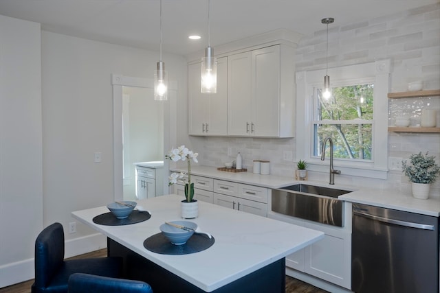 kitchen featuring tasteful backsplash, sink, dishwasher, a kitchen island, and white cabinets