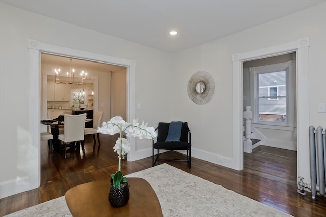 sitting room with an inviting chandelier, radiator heating unit, and dark wood-type flooring