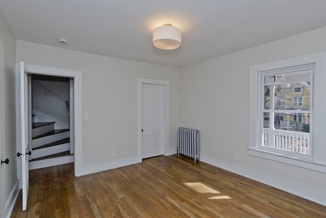 unfurnished bedroom featuring radiator heating unit and dark hardwood / wood-style floors