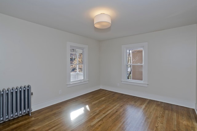 empty room featuring radiator heating unit and dark hardwood / wood-style floors