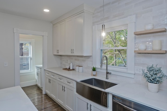 kitchen featuring tasteful backsplash, sink, dishwasher, white cabinetry, and decorative light fixtures