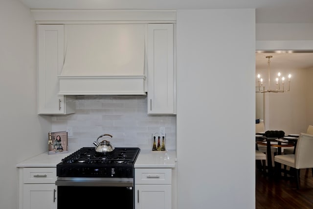 kitchen featuring dark hardwood / wood-style flooring, premium range hood, white cabinetry, a chandelier, and stainless steel gas stove