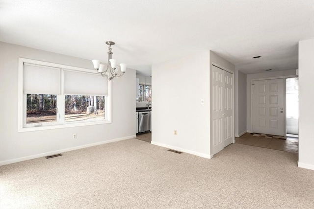 unfurnished living room featuring an inviting chandelier and carpet