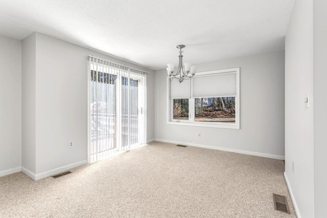 carpeted spare room featuring a notable chandelier