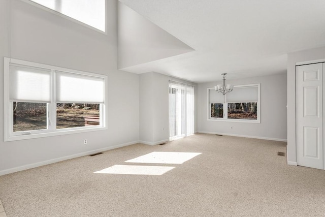 unfurnished living room with a chandelier and light colored carpet