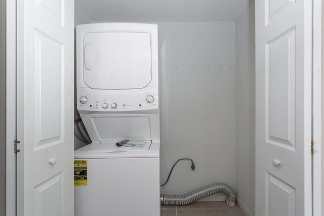 laundry area with stacked washer and clothes dryer and tile patterned floors