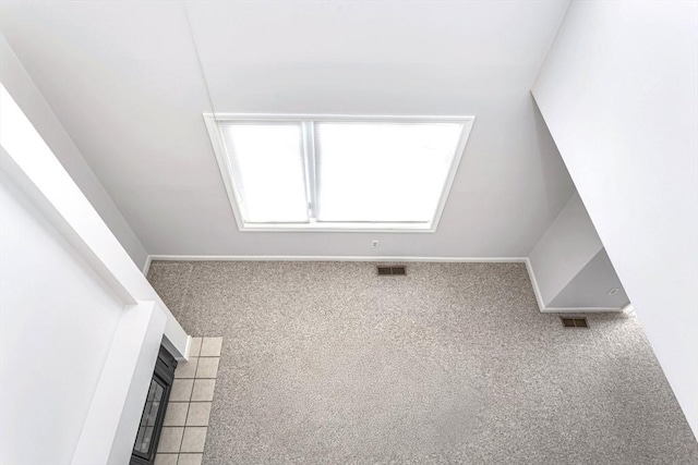 bonus room featuring a tiled fireplace and carpet flooring