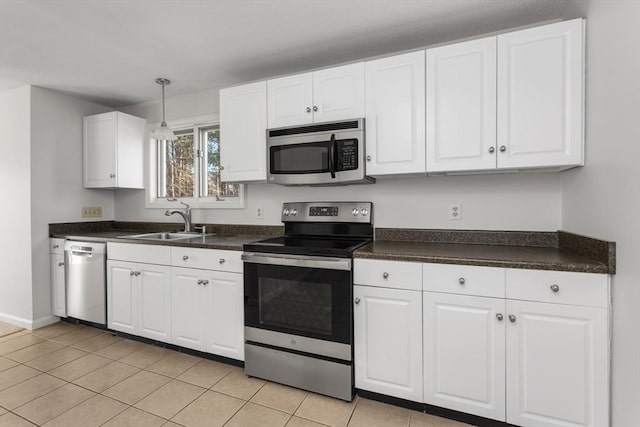 kitchen with stainless steel appliances, hanging light fixtures, sink, white cabinetry, and light tile patterned flooring