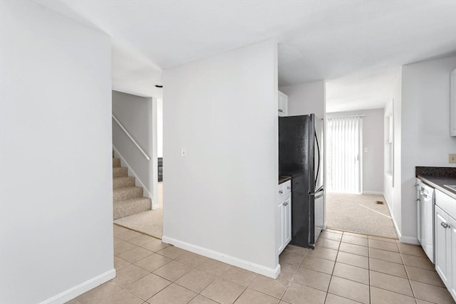 kitchen featuring white cabinets, black fridge, dishwasher, and light tile patterned floors