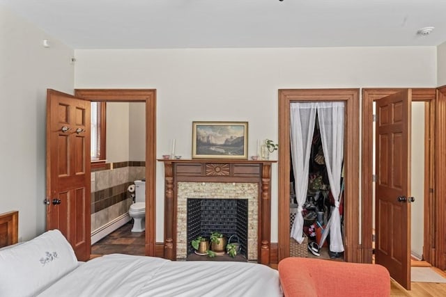 388 Arborway, Boston, MA 02130 - bedroom with a baseboard heating unit, connected bathroom, and wood finished floors