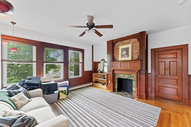388 Arborway, Boston, MA 02130 - living area featuring light wood-style flooring, ceiling fan, a wainscoted wall, a fireplace with flush hearth, and a baseboard radiator