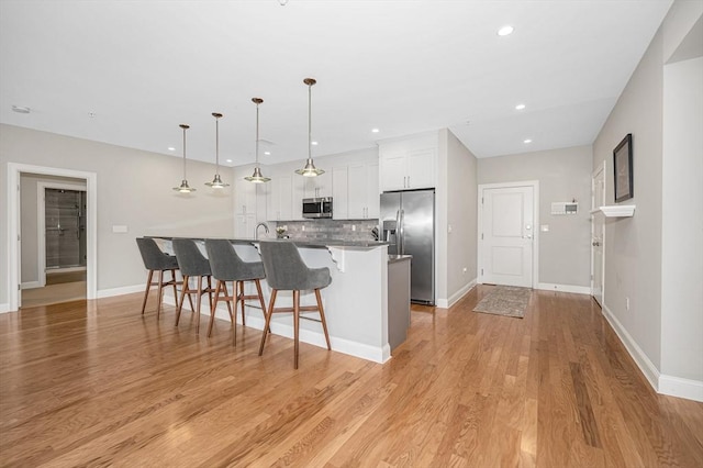 2 Inwood Dr Unit 3003, Woburn, MA 01801 - kitchen featuring stainless steel appliances, a kitchen bar, backsplash, white cabinets, and an island with sink