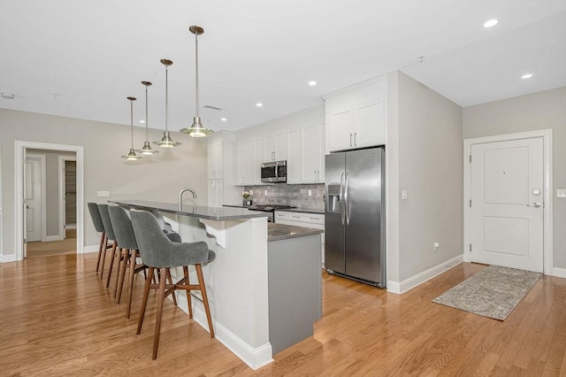 2 Inwood Dr Unit 3003, Woburn, MA 01801 - kitchen with stainless steel appliances, light wood-style flooring, baseboards, tasteful backsplash, and a kitchen bar