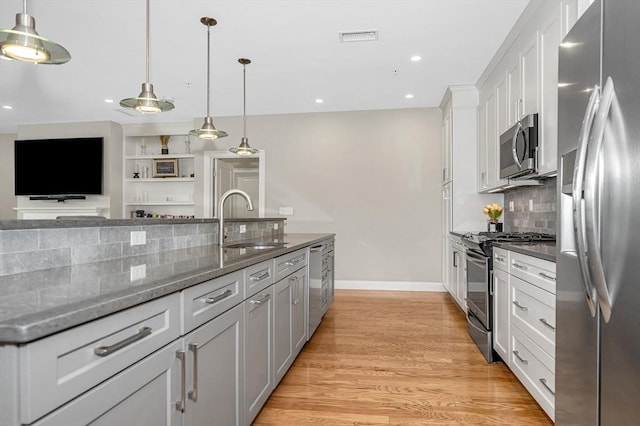 2 Inwood Dr Unit 3003, Woburn, MA 01801 - kitchen featuring appliances with stainless steel finishes, a sink, white cabinetry, light wood-style flooring, and backsplash