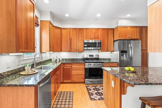 26-B Lake St Unit 26B, Somerville, MA 02143 - kitchen with stainless steel appliances, a sink, light wood-style floors, brown cabinetry, and dark stone counters
