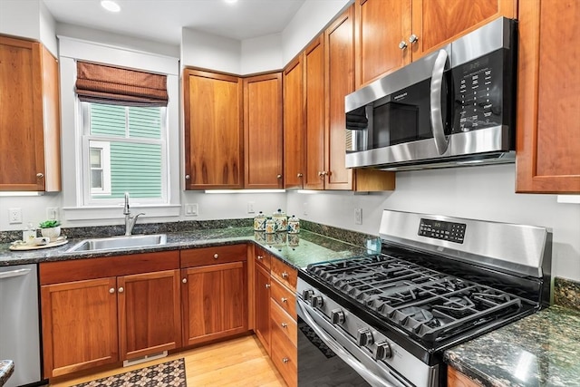 26-B Lake St Unit 26B, Somerville, MA 02143 - kitchen featuring appliances with stainless steel finishes, a sink, light wood-type flooring, dark stone countertops, and brown cabinets
