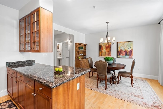 26-B Lake St Unit 26B, Somerville, MA 02143 - kitchen with light wood-style floors, a chandelier, dark stone countertops, and glass insert cabinets