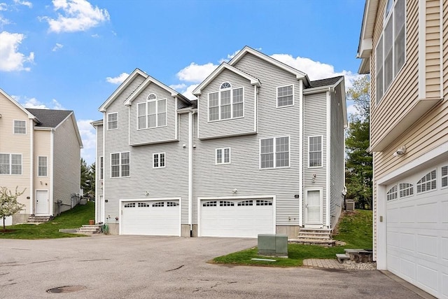 back of property featuring entry steps, cooling unit, aphalt driveway, and a garage