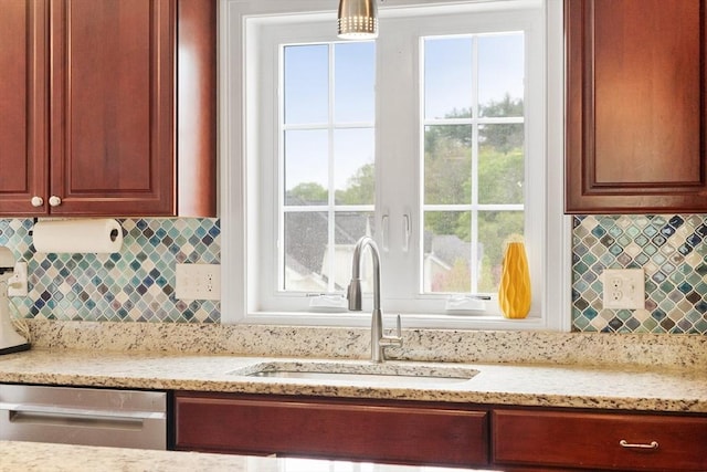 interior space with dishwasher, decorative backsplash, light stone counters, and a sink