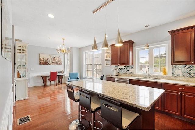 kitchen featuring an inviting chandelier, visible vents, a sink, backsplash, and dark wood-style floors