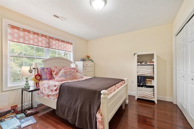 bedroom with a closet, visible vents, baseboards, and dark wood-style floors