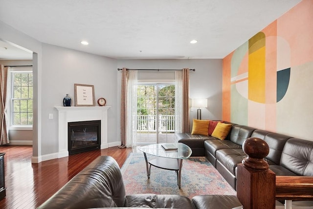 living room with baseboards, a glass covered fireplace, recessed lighting, and wood finished floors