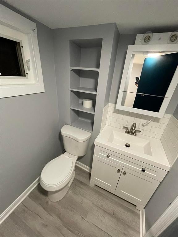 7 Coolidge St, Hudson, MA 01749 - half bathroom with toilet, vanity, wood finished floors, baseboards, and tasteful backsplash