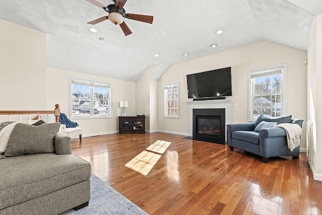 living room with hardwood / wood-style flooring, ceiling fan, and lofted ceiling