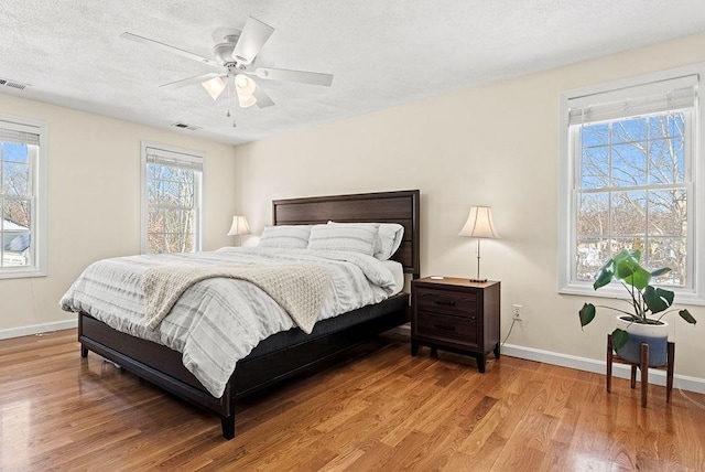 bedroom with hardwood / wood-style flooring, ceiling fan, and a textured ceiling