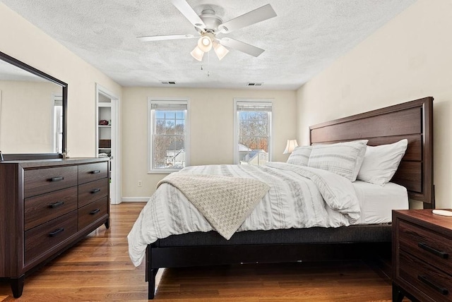 bedroom with ceiling fan, a textured ceiling, and light wood-type flooring