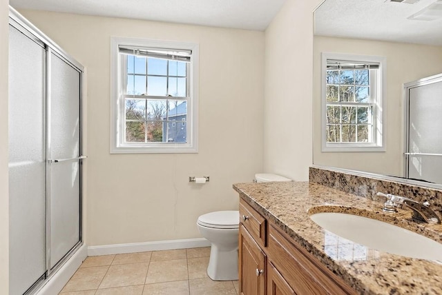 bathroom with tile patterned floors, vanity, toilet, and a shower with door