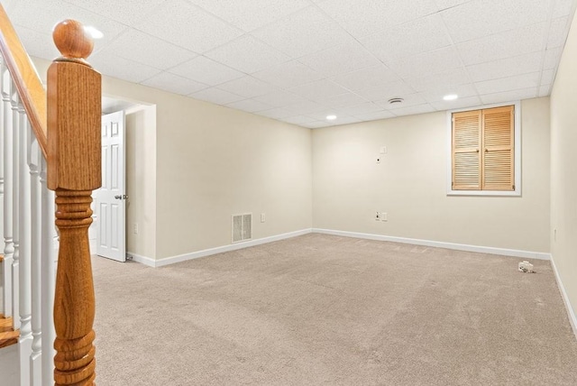 carpeted spare room featuring a drop ceiling