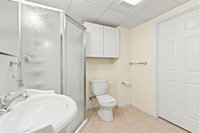 bathroom featuring a paneled ceiling, sink, an enclosed shower, toilet, and tile patterned floors