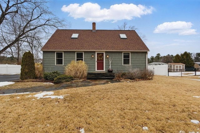 view of front of home with fence, a chimney, and a front lawn