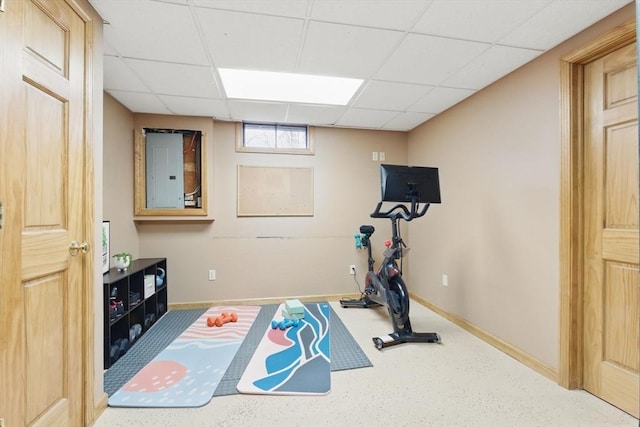 workout room featuring a paneled ceiling and baseboards