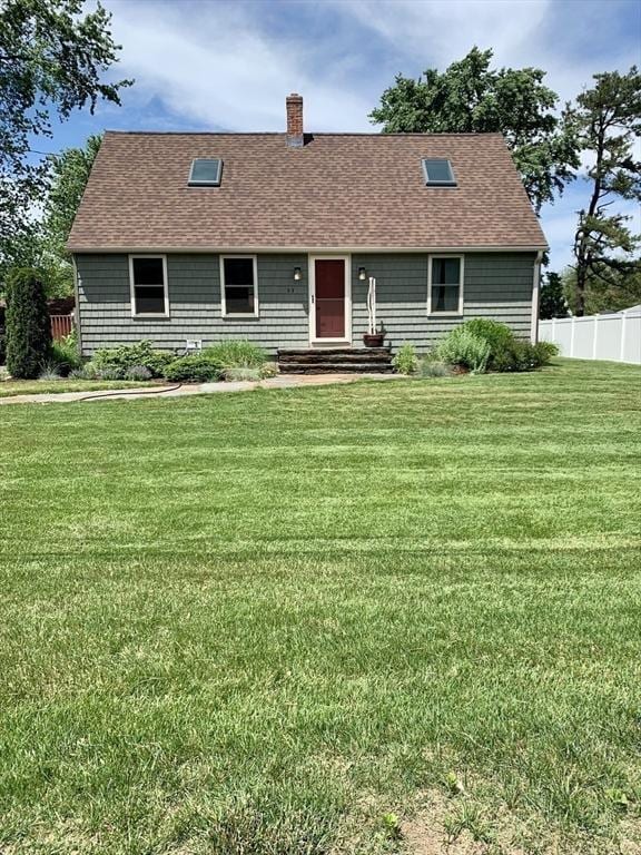 view of front of house featuring a chimney, fence, a front lawn, and roof with shingles