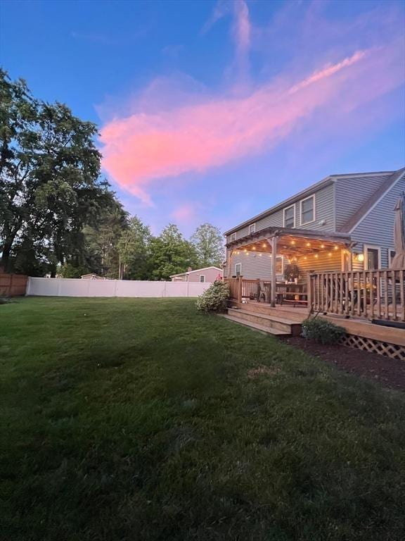 yard at dusk featuring fence and a wooden deck