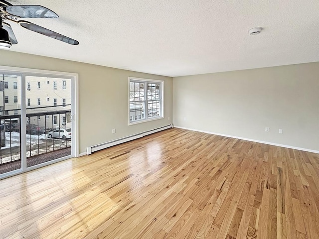 unfurnished room featuring a baseboard radiator, light wood-style flooring, baseboards, and a textured ceiling