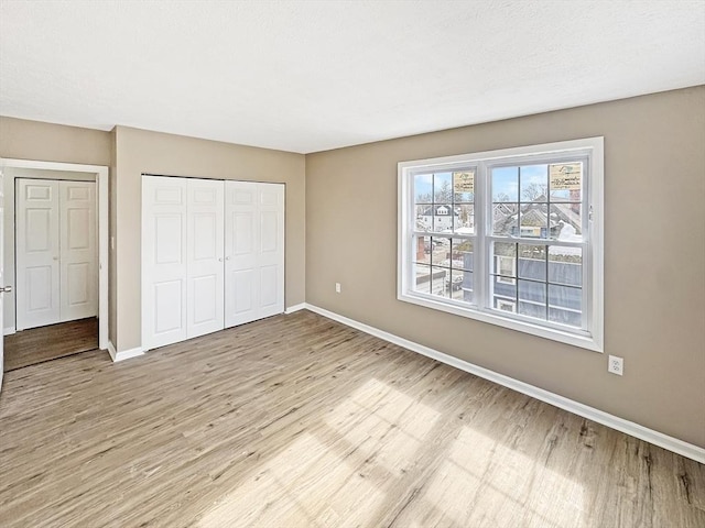 unfurnished bedroom with a closet, light wood-style flooring, and baseboards