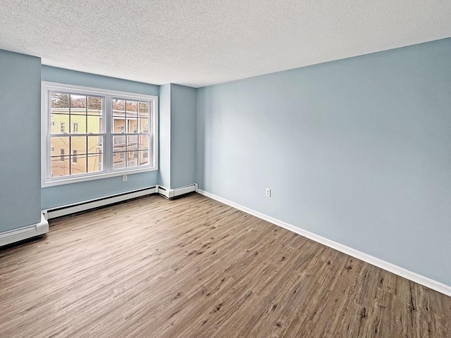 spare room with a textured ceiling, a baseboard radiator, wood finished floors, and baseboards