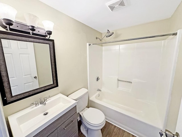 bathroom with visible vents, toilet, wood finished floors,  shower combination, and vanity