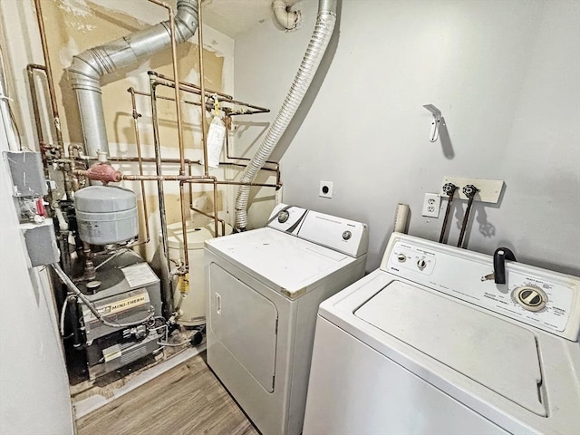 laundry area with laundry area, wood finished floors, a heating unit, and washing machine and dryer