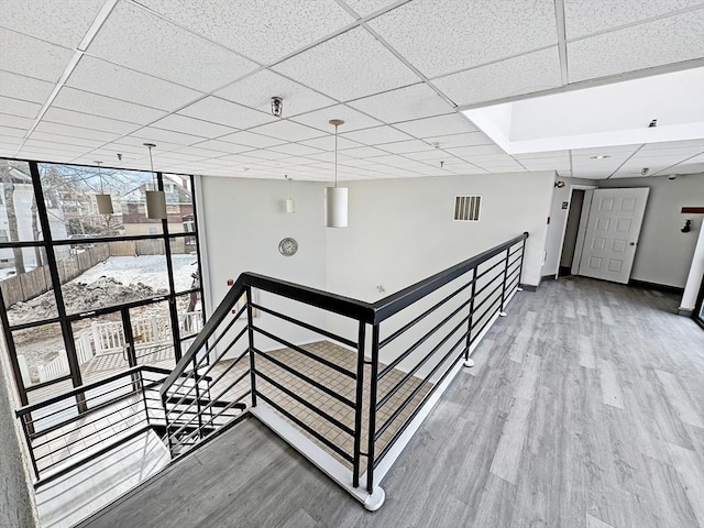 hallway featuring baseboards, visible vents, an upstairs landing, and wood finished floors