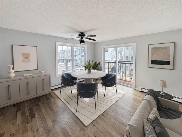 dining space with a baseboard heating unit, a textured ceiling, and wood finished floors